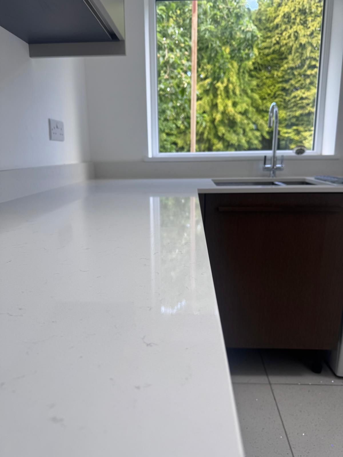 Bright, freshly cleaned kitchen worktop and sink by a sunlit window