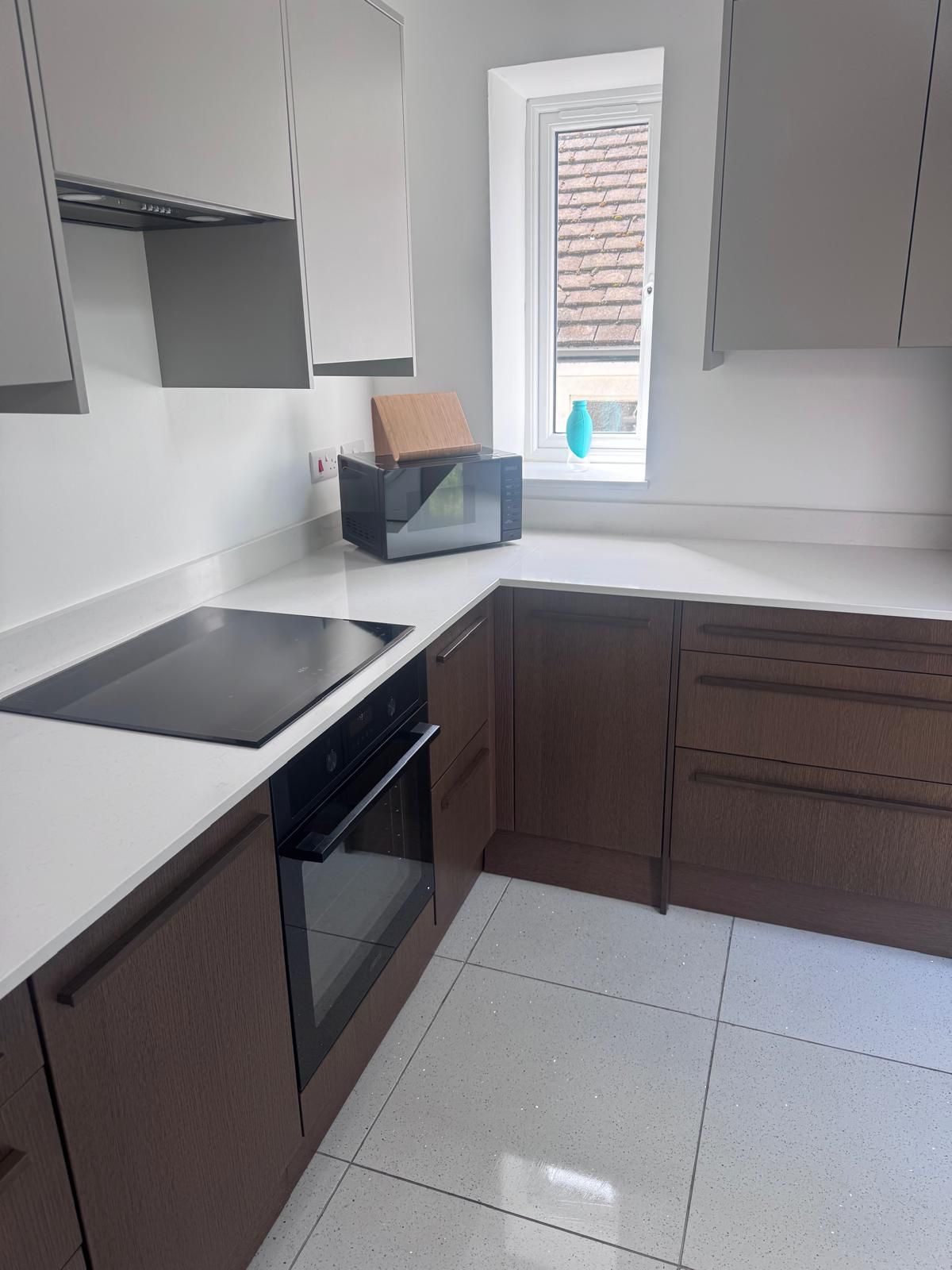A spotless modern kitchen with dark wood units, polished worktops and a clean hob, cleaned by Pure Luxe in Newport
