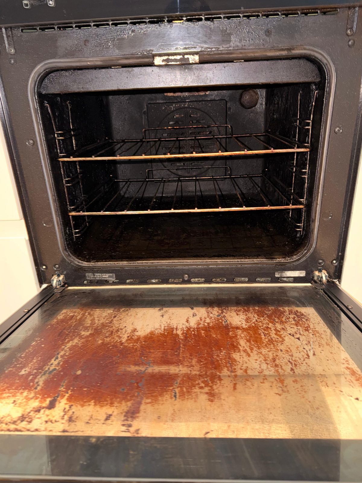 Oven interior before deep clean — burnt-on grease, carbon and a rusty base