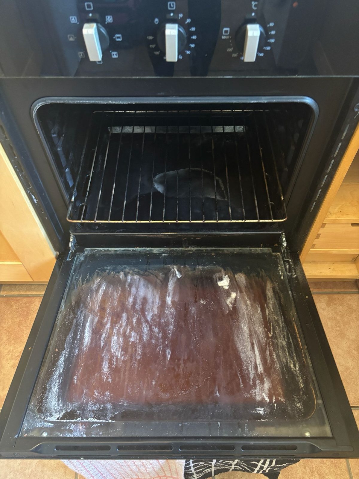 Open oven door revealing a freshly cleaned, gleaming interior after a Pure Luxe oven clean